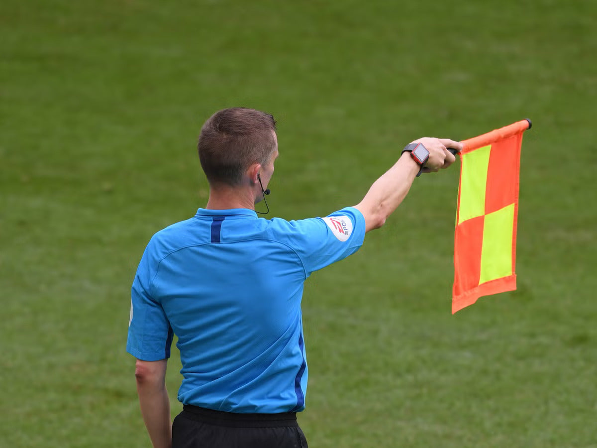 a soccer football referee raising his flag to signal an offside